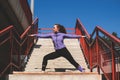 Young woman in sportswear doing a stretch on the stairs, urban yoga active lifestyle concept