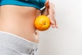 A young woman in sportswear holds an orange on her stomach Royalty Free Stock Photo