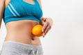 A young woman in sportswear holds an orange on her stomach Royalty Free Stock Photo