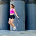 A young woman in sportswear jumps on a rope in the street