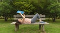 Young woman in sportswear lying on the wooden bench reading a book Royalty Free Stock Photo