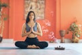 Young woman in sportswear, practicing yoga, sitting on the mat in the lotus position, is engaged in meditation with namaste Royalty Free Stock Photo