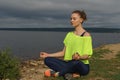 Young woman in sportswear sitting on river shore Royalty Free Stock Photo