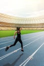 Young woman in sportswear sprinting on running track stadium at sunset Royalty Free Stock Photo