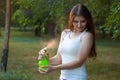 Young woman spraying water on herself from a spray bottle in a summer park Royalty Free Stock Photo