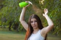 Young woman spraying water on herself from a spray bottle in a summer park Royalty Free Stock Photo