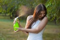 Young woman spraying water on herself from a spray bottle in a summer park Royalty Free Stock Photo