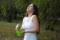 Young woman spraying water on herself from a spray bottle in a summer park Royalty Free Stock Photo