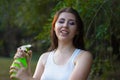 Young woman spraying water on herself from a spray bottle in a summer park Royalty Free Stock Photo