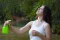 Young woman spraying water on herself from a spray bottle in a summer park Royalty Free Stock Photo