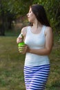 Young woman spraying water on herself from a spray bottle in a summer park Royalty Free Stock Photo