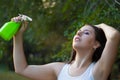 Young woman spraying water on herself from a spray bottle in a summer park Royalty Free Stock Photo