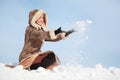 Young woman squatting and hands throw snow