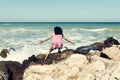 Young woman squatting on a sea beach enjoying the beautiful sunny weather Royalty Free Stock Photo