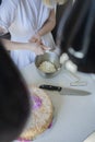 A young woman squeezes cream into a bowl.