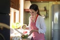 Young woman squeezing fresh lemon over bowl with salad at countertop in kitchen Royalty Free Stock Photo