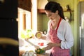 Young woman squeezing fresh lemon over bowl with salad at countertop Royalty Free Stock Photo