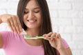 Young woman squeezing toothpaste on brush against blurred background Royalty Free Stock Photo