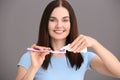 Young woman squeezing toothpaste on brush against grey background Royalty Free Stock Photo