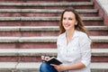 Young woman on stairs and making notes in notebook Royalty Free Stock Photo