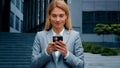 Young woman stand on downtown with phone in hands typing business email answering message in social media smiling Royalty Free Stock Photo