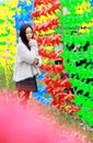 A young woman stand in front of colorful windmills