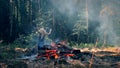 A young woman stand near fire and raises her hands and lowers them