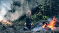 A young woman stand near fire and raises her hands and lowers them