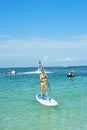 Young woman stand up on board and man posing at new flyboard at Caribbean tropical beach. Standup paddleboarding. Positive human e Royalty Free Stock Photo