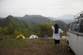 Young woman standing with adventure car against mountains view in the morning. A Girl showing happiness and gratitude.