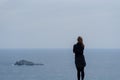 Young woman standing against a blue sky and sea