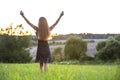 Young woman standing alone on a field with green grass enjoying warm sunset Royalty Free Stock Photo