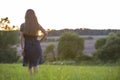 Young woman standing alone on a field with green grass enjoying warm sunset Royalty Free Stock Photo