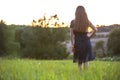 Young woman standing alone on a field with green grass enjoying warm sunset Royalty Free Stock Photo