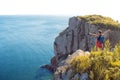 Young woman standing alone on a rocky cliff, arms outstretched. Girl tourist on the background of beautiful wildlife Royalty Free Stock Photo