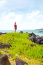 Young woman standing along rocky shore looking out towards ocean Royalty Free Stock Photo