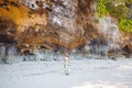 Young woman standing on the beach in front of the rocks Royalty Free Stock Photo