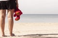 Young woman standing on the beach with a red teddy bear in hand