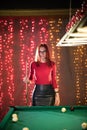 A young woman standing in billiard club holding a cue Royalty Free Stock Photo
