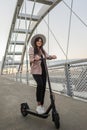 A young woman standing on the bridge next to her electric scooter Royalty Free Stock Photo