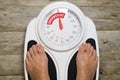 Young woman standing on classic analogue weight scale indicating overweight