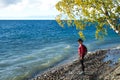 Young woman standing on the coast of Baikal lake at sunrise in autumn. Siberia, Russia. Landscape with girl in red Royalty Free Stock Photo