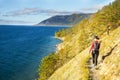 Young woman standing on the coast of Baikal lake at sunrise in autumn. Siberia, Russia. Landscape with girl in red Royalty Free Stock Photo