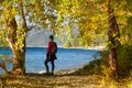 Young woman standing on the coast of Baikal lake at sunrise in autumn. Siberia, Russia. Landscape with girl in red Royalty Free Stock Photo