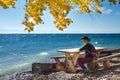 Young woman standing on the coast of Baikal lake at sunrise in autumn. Siberia, Russia. Landscape with girl in red Royalty Free Stock Photo