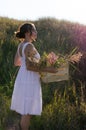 A young woman standing in the field holding a wooden box full of flowers during the sunset. Royalty Free Stock Photo