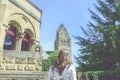 Young woman is standing in front of the old building with a old church nearby