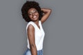 Young woman standing on gray touching hair smiling happy