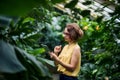 Young woman standing in greenhouse in botanical garden, using tablet. Royalty Free Stock Photo