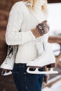 Young woman standing with her ice skates slung over her shoulder